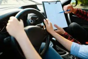 driving instructor with a checklist measuring student performance on driving