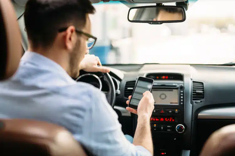 man using phone while driving a car